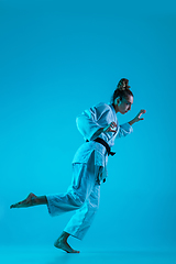 Image showing Young girl professional judoist isolated on blue studio background in neon light. Healthy lifestyle, sport concept.