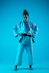 Image showing Portrait of professional female judoist isolated on blue studio background in neon light. Healthy lifestyle, sport concept.