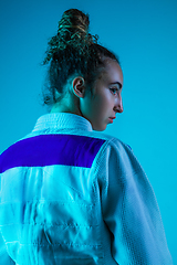 Image showing Portrait of professional female judoist isolated on blue studio background in neon light. Healthy lifestyle, sport concept.