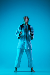 Image showing Young girl professional judoist isolated on blue studio background in neon light. Healthy lifestyle, sport concept.