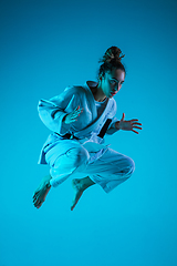 Image showing Young girl professional judoist isolated on blue studio background in neon light. Healthy lifestyle, sport concept.