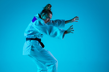 Image showing Young girl professional judoist isolated on blue studio background in neon light. Healthy lifestyle, sport concept.