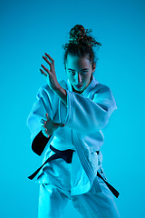 Image showing Young girl professional judoist isolated on blue studio background in neon light. Healthy lifestyle, sport concept.