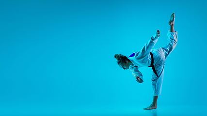 Image showing Professional female judoist posing isolated on blue studio background in neon light. Flyer for ad, design.