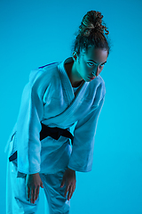 Image showing Professional female judoist training isolated on blue studio background in neon light. Healthy lifestyle, sport concept.