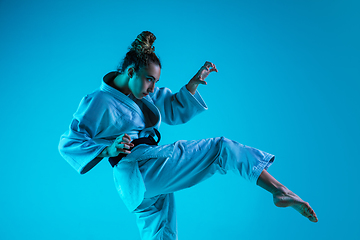 Image showing Young girl professional judoist isolated on blue studio background in neon light. Healthy lifestyle, sport concept.