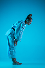 Image showing Professional female judoist training isolated on blue studio background in neon light. Healthy lifestyle, sport concept.