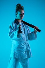 Image showing Young girl professional judoist isolated on blue studio background in neon light. Healthy lifestyle, sport concept.