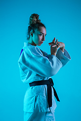 Image showing Professional female judoist posing isolated on blue studio background in neon light. Healthy lifestyle, sport concept.