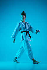 Image showing Professional female judoist posing isolated on blue studio background in neon light. Healthy lifestyle, sport concept.