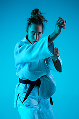 Image showing Young girl professional judoist isolated on blue studio background in neon light. Healthy lifestyle, sport concept.