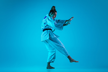 Image showing Young girl professional judoist isolated on blue studio background in neon light. Healthy lifestyle, sport concept.