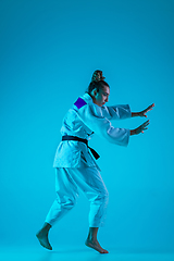 Image showing Young girl professional judoist isolated on blue studio background in neon light. Healthy lifestyle, sport concept.