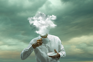 Image showing Contemporary art collage. Male body of model with head full of smoke about sky and clouds drinking tea.