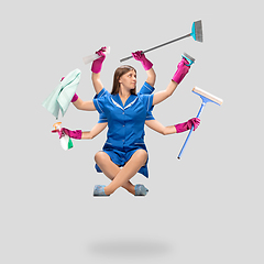 Image showing Female housemaid in pink gloves and blue uniform multitask like shiva isolated on gray background. Human emotions.