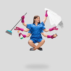 Image showing Female housemaid in pink gloves and blue uniform multitask like shiva isolated on gray background. Human emotions.