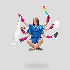 Image showing Female housemaid in pink gloves and blue uniform multitask like shiva isolated on gray background. Human emotions.