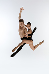 Image showing Two graceful ballet dancers man and woman in minimal black style dancing isolated on white studio background