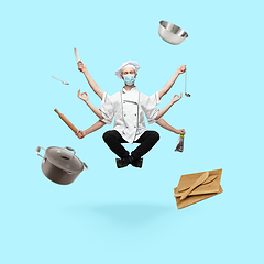 Image showing Young handsome multi-armed cooker in face mask levitating isolated on blue studio background with equipment