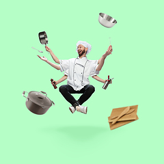 Image showing Happy handsome multi-armed chief-cooker levitating isolated on green studio background with equipment