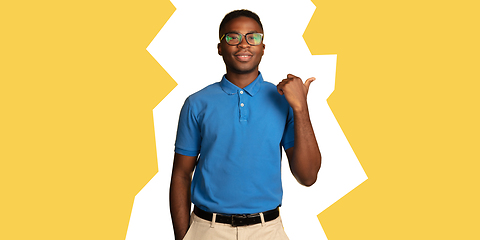 Image showing Young african-american man\'s portrait isolated on yellow studio background, facial expression. Magazine style concept.