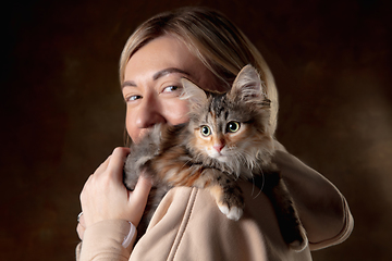 Image showing A small purebred kitten sitting on the shoulder of a young woman isolated on colored background. Flyer for ad, design.