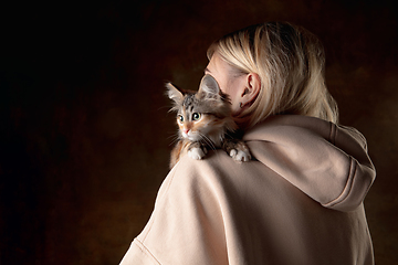 Image showing A small purebred kitten sitting on the shoulder of a young woman isolated on colored background. Flyer for ad, design.