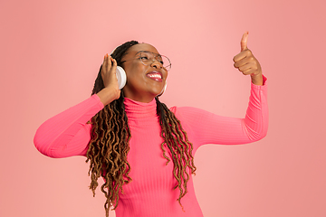 Image showing Young african-american woman\'s portrait isolated on pink studio background, facial expression. Beautiful female half-lenght portrait with copyspace.