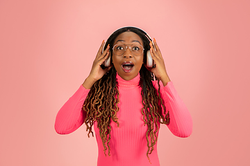 Image showing Young african-american woman\'s portrait isolated on pink studio background, facial expression. Beautiful female half-lenght portrait with copyspace.