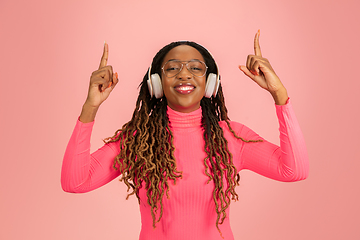 Image showing Young african-american woman\'s portrait isolated on pink studio background, facial expression. Beautiful female half-lenght portrait with copyspace.