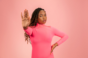 Image showing Portrait of young african-american woman isolated on pink studio background, facial expression. Beautiful female half-lenght portrait with copyspace.