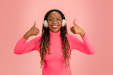Image showing Young african-american woman\'s portrait isolated on pink studio background, facial expression. Beautiful female half-lenght portrait with copyspace.