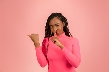 Image showing Young african-american woman isolated on pink studio background, facial expression. Beautiful female half-lenght portrait with copyspace.