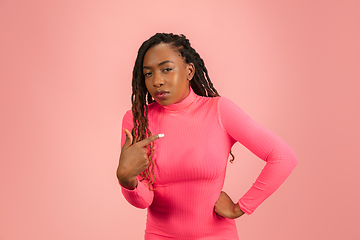 Image showing Portrait of young african-american woman isolated on pink studio background, facial expression. Beautiful female half-lenght portrait with copyspace.