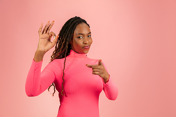 Image showing Portrait of young african-american woman isolated on pink studio background, facial expression. Beautiful female half-lenght portrait with copyspace.