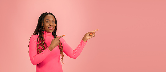 Image showing Portrait of young african-american woman isolated on pink studio background, facial expression. Beautiful female half-lenght portrait with copyspace.