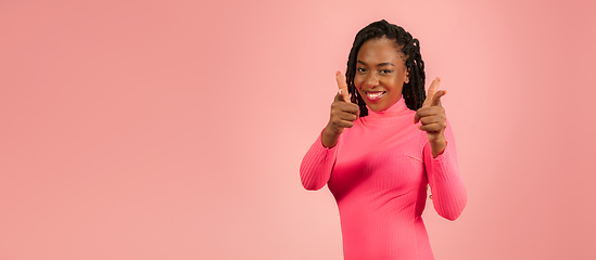 Image showing Portrait of young african-american woman isolated on pink studio background, facial expression. Beautiful female half-lenght portrait with copyspace.