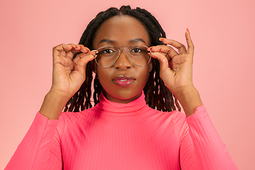 Image showing Portrait of young beautiful african-american woman isolated on pink studio background, facial expression. Half-lenght portrait with copyspace.