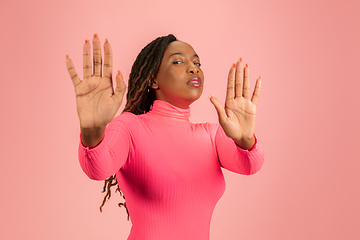 Image showing Portrait of young african-american woman isolated on pink studio background, facial expression. Beautiful female half-lenght portrait with copyspace.