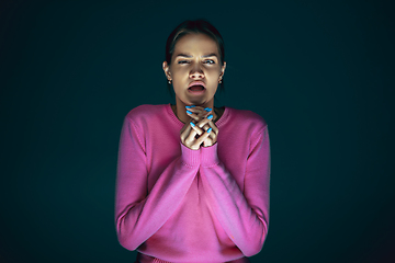 Image showing Close up portrait of young crazy scared and shocked woman isolated on dark background