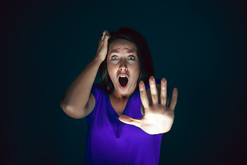 Image showing Close up portrait of young crazy scared and shocked woman isolated on dark background