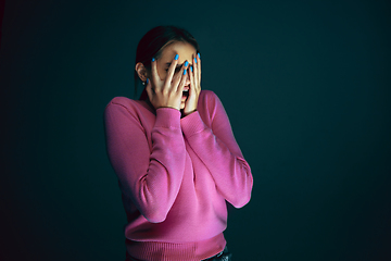 Image showing Close up portrait of young crazy scared and shocked woman isolated on dark background