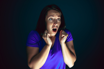 Image showing Close up portrait of young crazy scared and shocked woman isolated on dark background