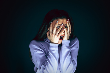 Image showing Close up portrait of young crazy scared and shocked woman isolated on dark background