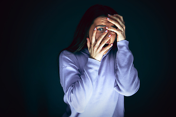 Image showing Close up portrait of young crazy scared and shocked woman isolated on dark background