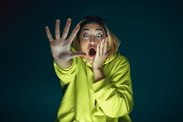 Image showing Close up portrait of young crazy scared and shocked woman isolated on dark background