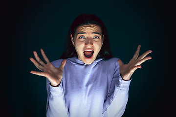 Image showing Close up portrait of young crazy scared and shocked woman isolated on dark background