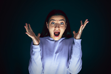 Image showing Close up portrait of young crazy scared and shocked woman isolated on dark background