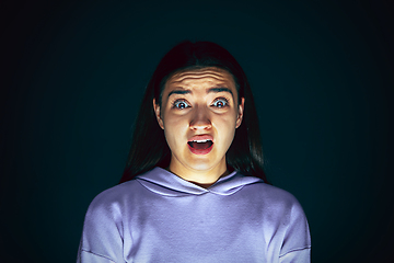 Image showing Close up portrait of young crazy scared and shocked woman isolated on dark background