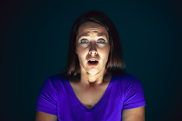 Image showing Close up portrait of young crazy scared and shocked woman isolated on dark background